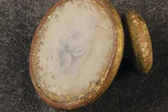 This is a small brass button or stud (possibly from a shirt) with mother-of-pearl inlay. Buttons made from gold or silver were often status symbols.